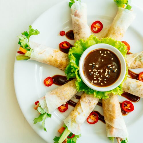 Duck meat inside spring roll with vegetable and sweet sauce in white plate